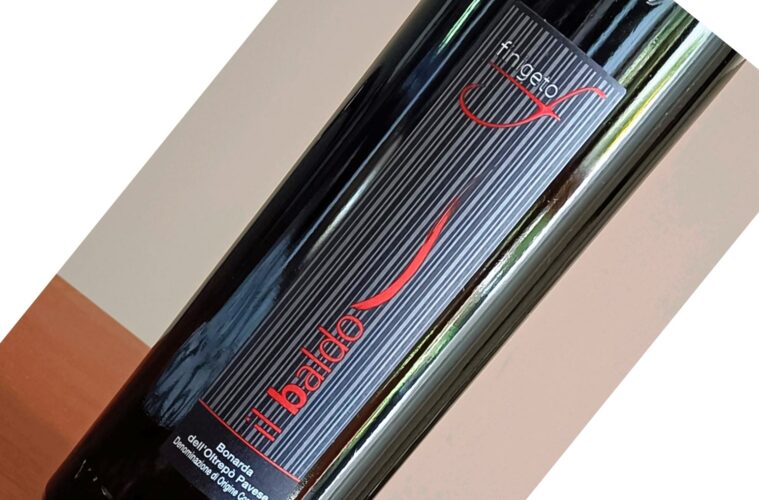 Close-up of a dark wine bottle with a vertically striped black label, a red logo, and the text 'Il Badardo' visible.