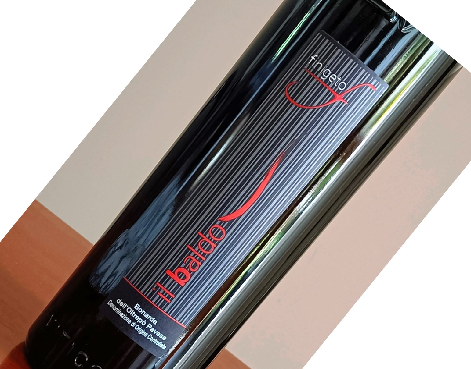 Close-up of a dark wine bottle with a vertically striped black label, a red logo, and the text 'Il Badardo' visible.