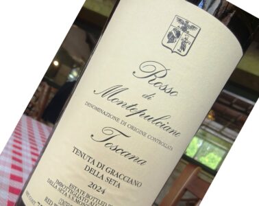 Close-up of a wine bottle label with a crest at the top and elegant cursive text, likely a Montepulciano red wine.