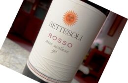 Wine bottle labeled Sette Soli Rosso with a sun emblem, Terre Siciliane IGT, tilted on a countertop