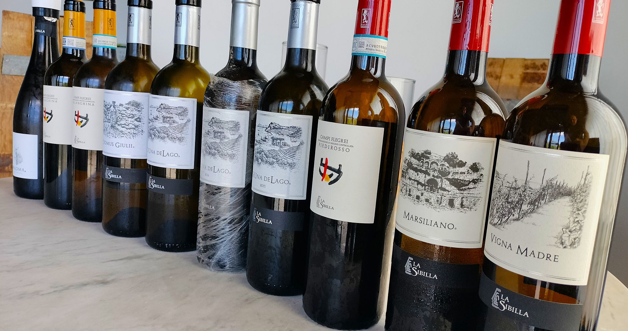 Row of wine bottles lined up on a marble surface, labels facing forward for display readout (red and white wines)