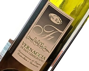 Wine bottle label reading 'VERNACCIA DI SAN GIMIGNANO' with skyline graphic and vintage seal, angled in a close-up view