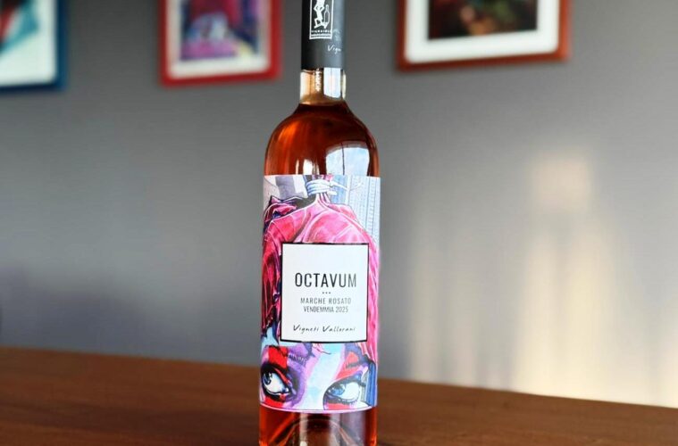 Rosé wine bottle on a wooden table with a colorful label reading 'OCTAVUM' and artwork in the background.