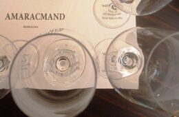 Top-down view of several empty wine glasses placed over a printed label that reads AMARACMAND ROMAGNA.