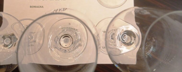 Top-down view of several empty wine glasses placed over a printed label that reads AMARACMAND ROMAGNA.