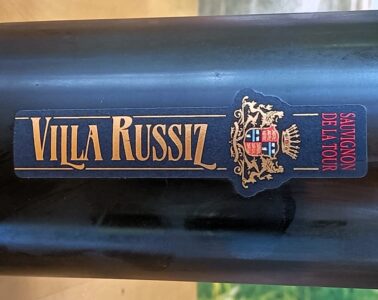 Dark wine bottle with a blue label reading 'SAUVIGNON DE LA TOUR' and a gold crest; vertical gold lettering along the label.