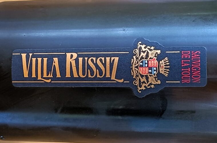 Dark wine bottle with a blue label reading 'SAUVIGNON DE LA TOUR' and a gold crest; vertical gold lettering along the label.