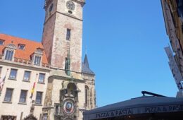 Historic clock tower (Old Town Hall) with an astronomical clock on a stone building against a clear blue sky.