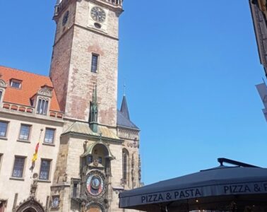 Historic clock tower (Old Town Hall) with an astronomical clock on a stone building against a clear blue sky.