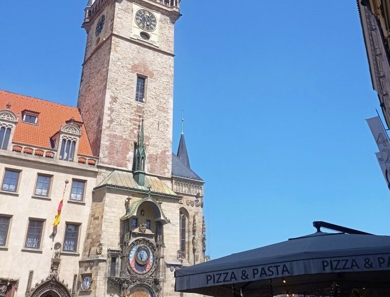Historic clock tower (Old Town Hall) with an astronomical clock on a stone building against a clear blue sky.