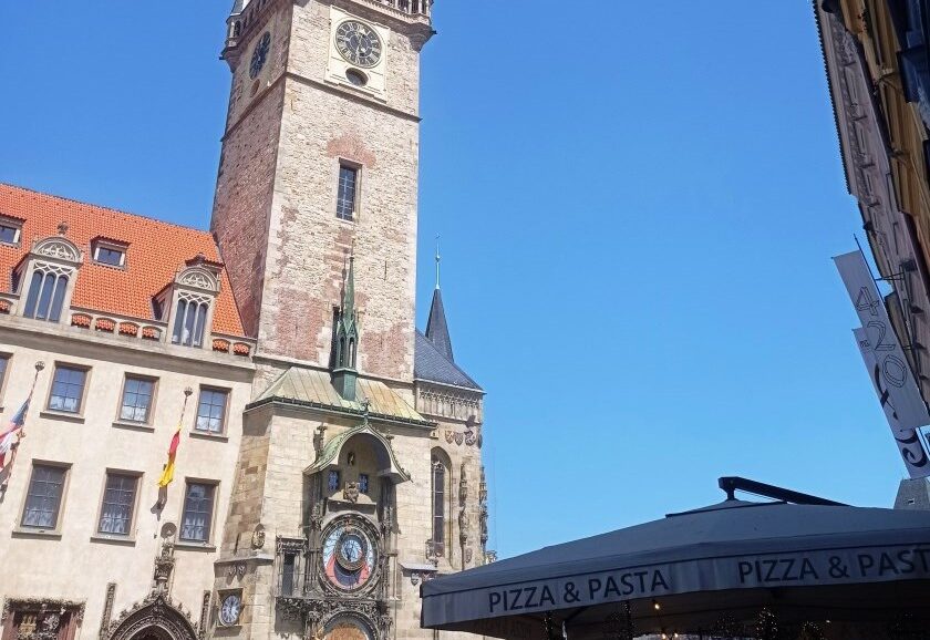Historic clock tower (Old Town Hall) with an astronomical clock on a stone building against a clear blue sky.
