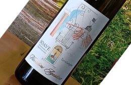 Bottle of wine on a wooden table with a decorative label featuring architectural motifs and the word 'Soave' (tilted in the photo).