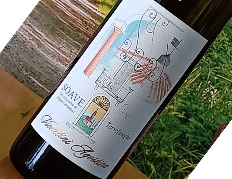 Bottle of wine on a wooden table with a decorative label featuring architectural motifs and the word 'Soave' (tilted in the photo).