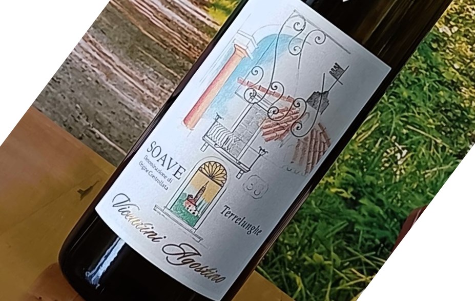 Bottle of wine on a wooden table with a decorative label featuring architectural motifs and the word 'Soave' (tilted in the photo).