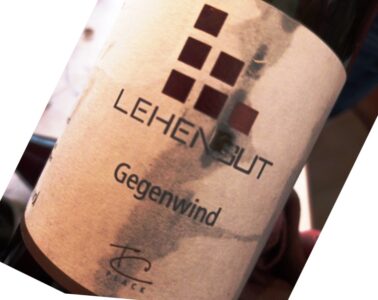 Close-up of a tilted wine bottle label with the word 'Gegenwind' and a grid of dark red squares.